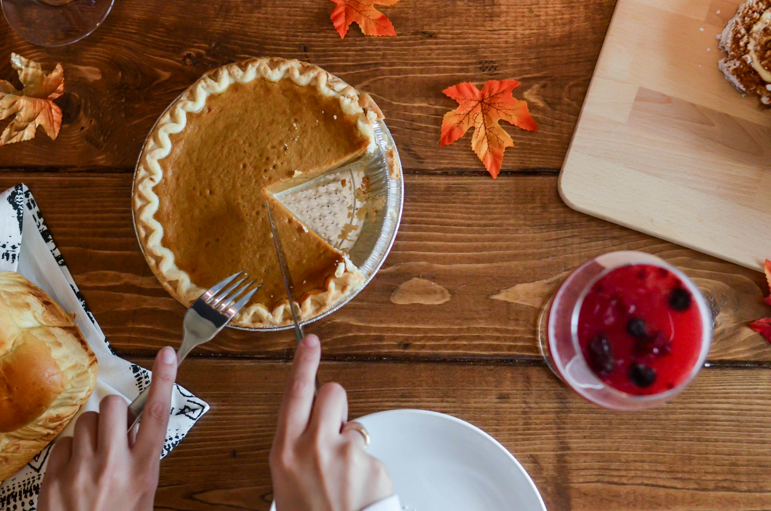 Autumn-themed flatlay of pumpkin pie with utensils on a wooden table.