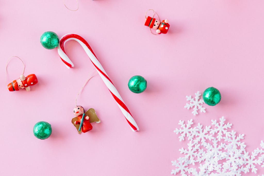 Christmas decorations including candy canes and ornaments on a pink background.