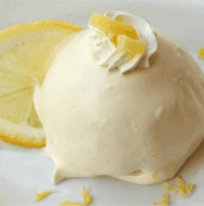 A picture of a lemon cake with lemon creamy lemon frosting and a lemon slice in the background.