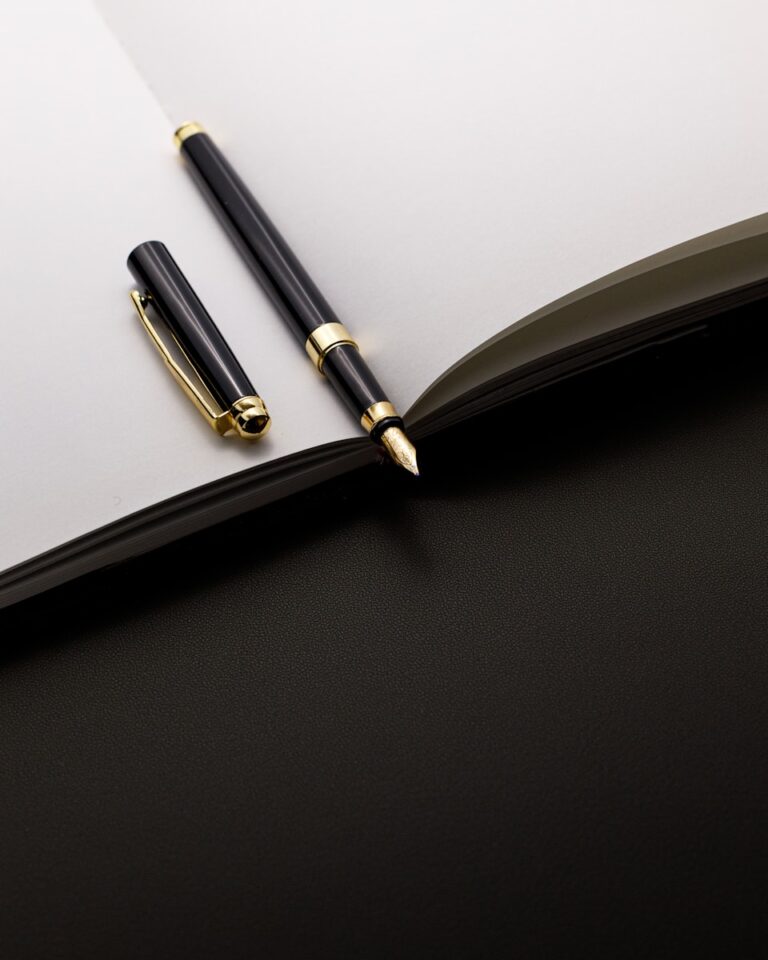 A black and gold pen rests on an open notebook.