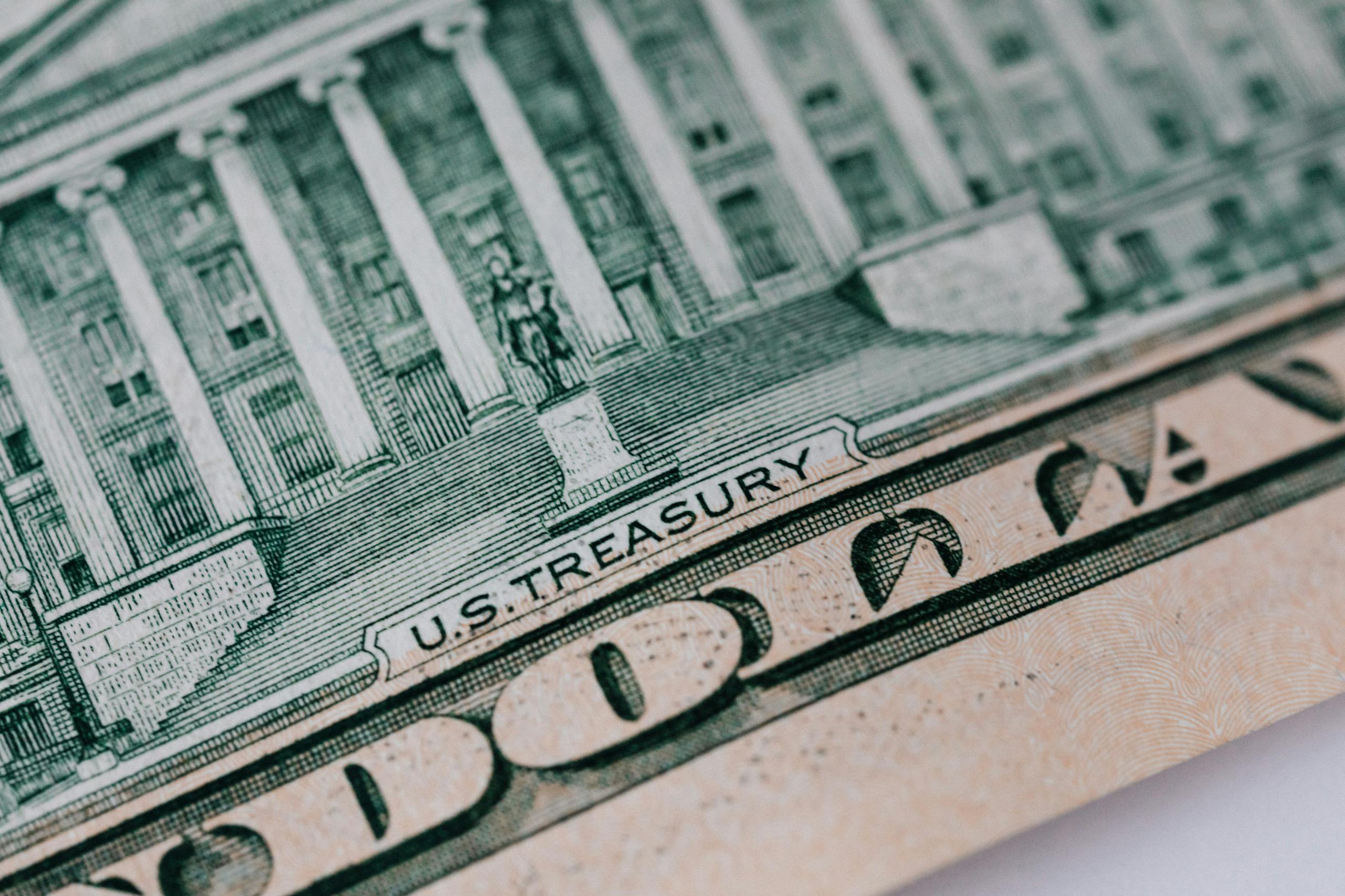Detailed close-up of the U.S. Treasury text on a dollar bill, showcasing intricate design and financial symbolism.
