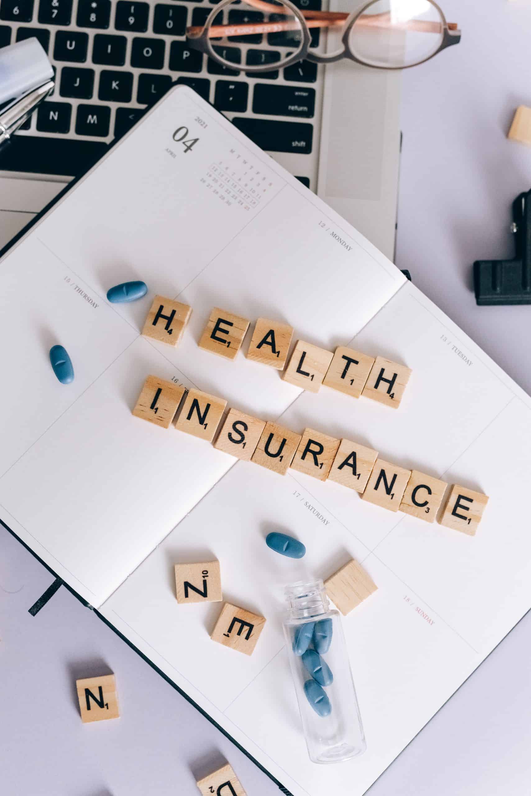 Flat lay of health insurance concept with pills, glasses, and notebook for business use.